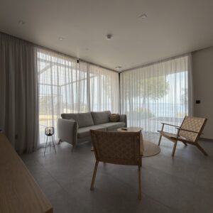 Villa 2 in Vourvourou, Halkidiki, featuring a bright living area with sofa, armchairs, and large windows with outdoor views.